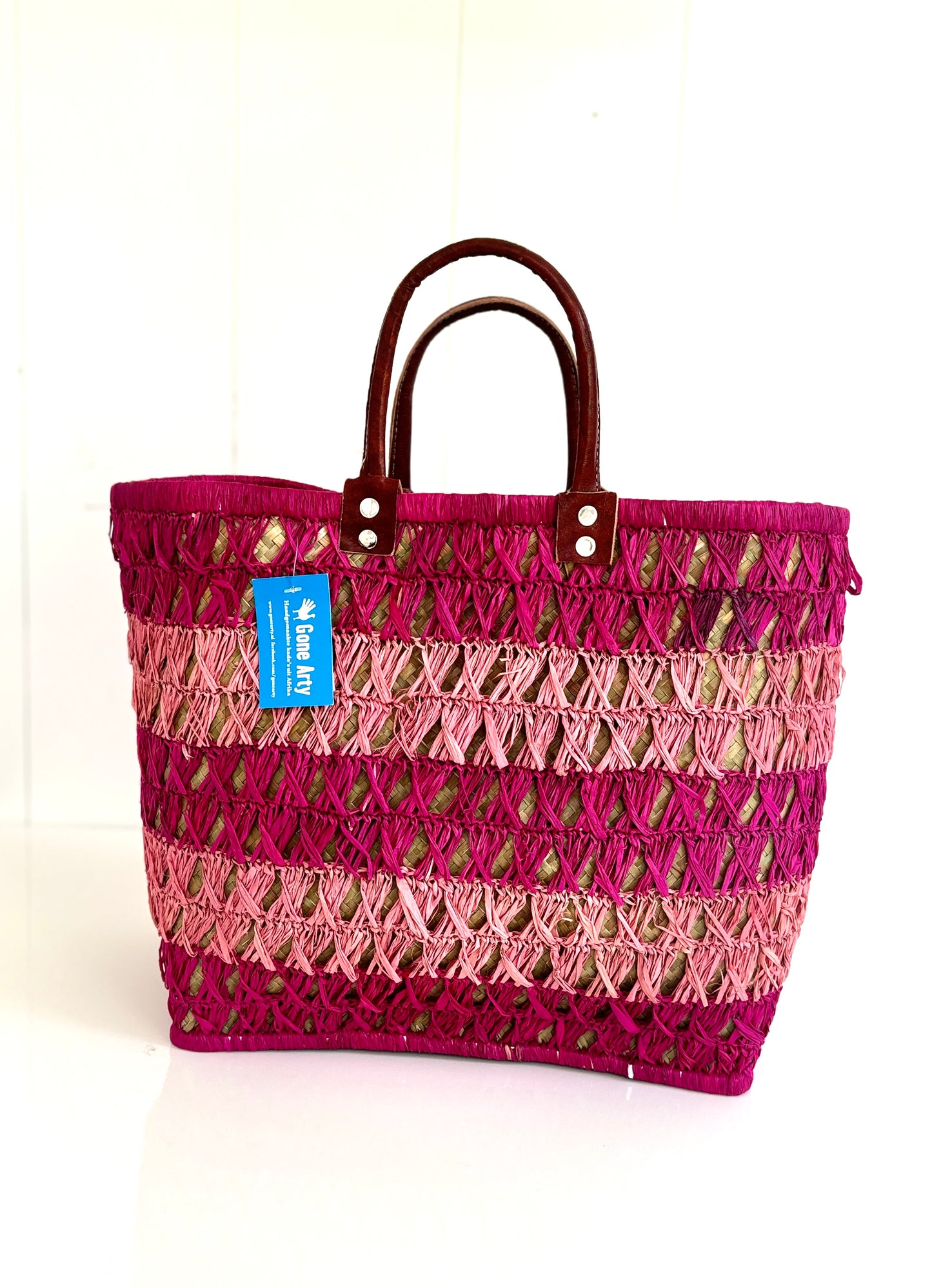 Fairtrade mand van gevlochten riet en roze raffia.